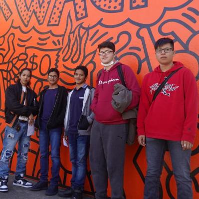 Members posing in front of the orange side of Keith Haring's Crack is Wack Mural